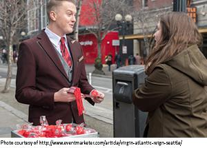 Virgin Atlantic flight attendant giving sample to woman while standing on city sidewalk